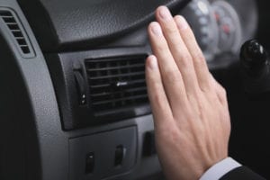 Hand feeling the air coming out of a car air vent